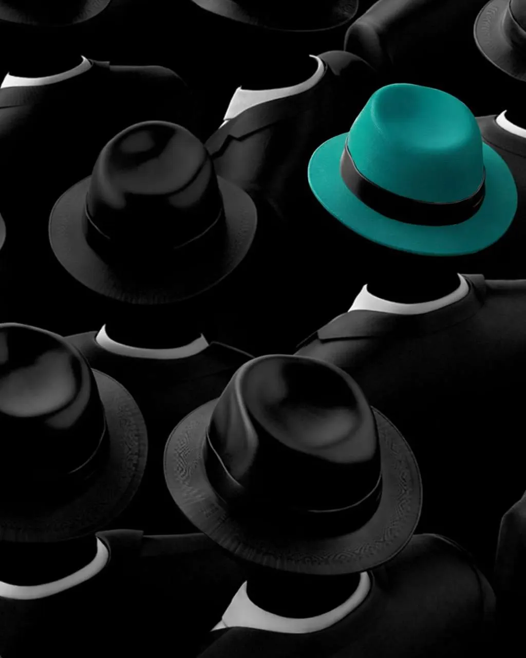 A crowd of identical black hats with a single teal hat standing out