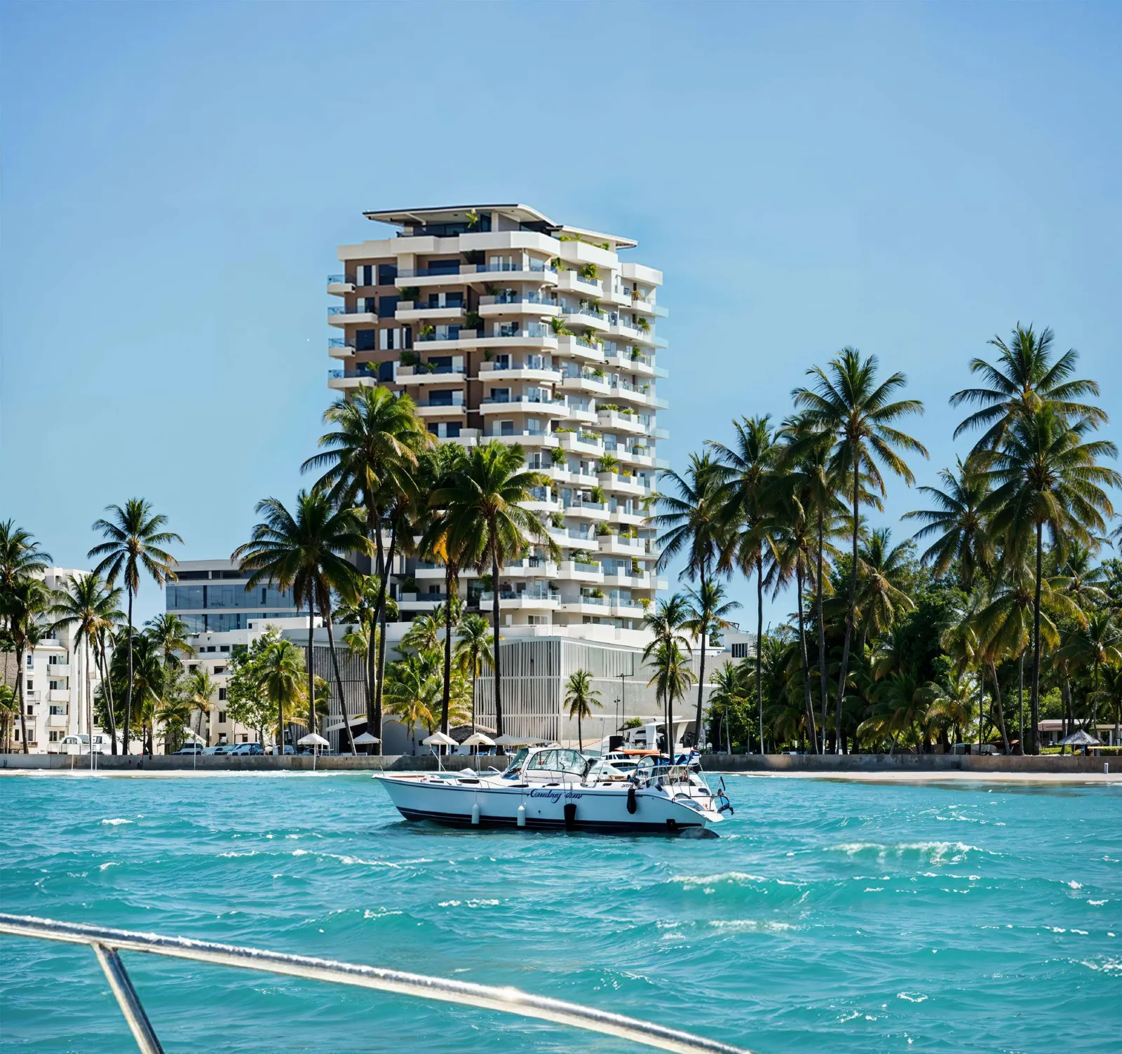 Architectural render: a white 15-storey tropical residential tower with plants on the balconies, seen from turquoise water with palm trees and a motorboat in the foreground.